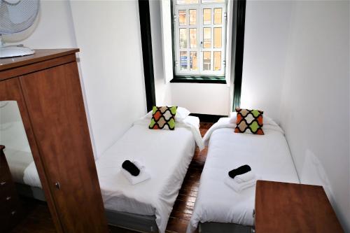 2 Betten in einem kleinen Zimmer mit Fenster in der Unterkunft Family Bedroom in Lissabon