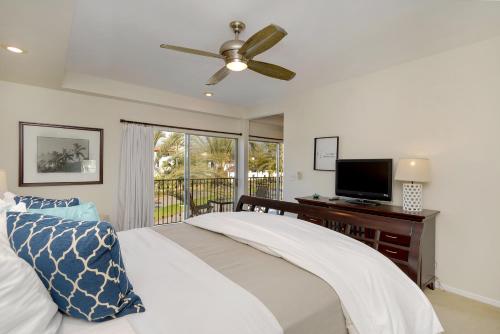 a bedroom with a bed with a ceiling fan and a television at 633 Top Floor Corner Condo inside the gates of the Resort in Encinitas