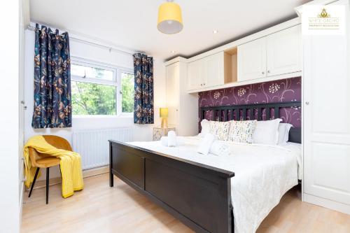 a bedroom with a large bed with a purple headboard at 4 Bed House Stevenage SG1 Free Parking & Wi-Fi Business & Families Serviced Accommodation by White Orchid Property Relocation in Stevenage