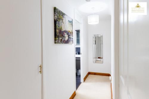 a hallway with a mirror and a painting on the wall at 4 Bed House Stevenage SG1 Free Parking & Wi-Fi Business & Families Serviced Accommodation by White Orchid Property Relocation in Stevenage