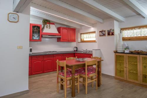 サン・ピエトロ・ディ・カドーレにあるAppartamenti Patriziaのキッチン(赤いキャビネット、テーブル、椅子付)