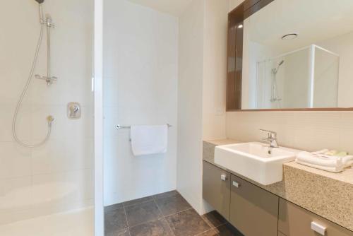 a white bathroom with a sink and a shower at StayCentral - Cityviews on City Road Southbank in Melbourne