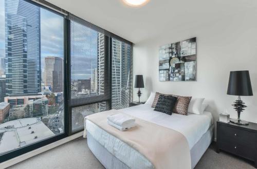 a bedroom with a large window with a view of a city at StayCentral - Cityviews on City Road Southbank in Melbourne