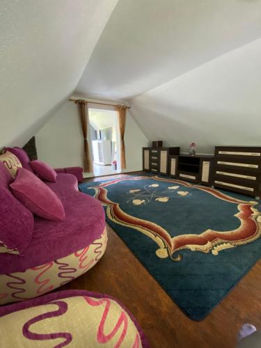 a living room with a purple couch and a rug at Agroturystyka ‚U Misia’ in Krzywopłoty