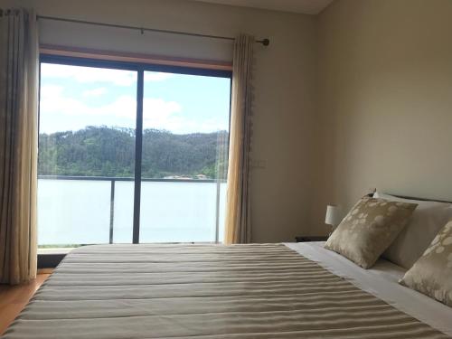 una camera da letto con un letto grande con una grande finestra di Casa do Pereiro a Vieira do Minho