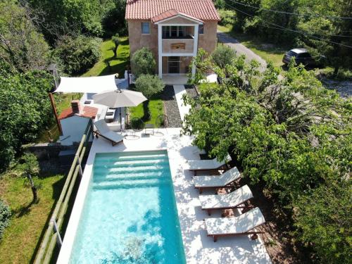 een luchtzicht op een zwembad met stoelen en een huis bij Wellness House Oliva with heated salt water Pool, Sauna & Jakuzzi in Labin