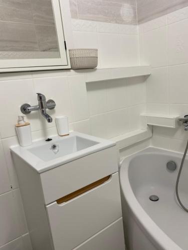a white bathroom with a sink and a bath tub at Apartament Długie Ogrody 54 in Gdańsk