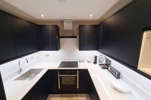 una cocina con armarios negros y fregadero en 39 steps to Harrods 2 Beds with AC en Londres