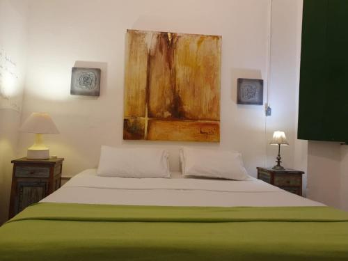 a bedroom with a bed and a painting on the wall at Apto com Arte no Pelourinho in Salvador