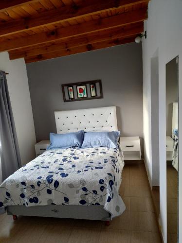 Schlafzimmer mit einem Bett mit einer blauen und weißen Bettdecke in der Unterkunft Casa Ana, departamento amplio a 20 ' aeropuerto in Luis Guillón