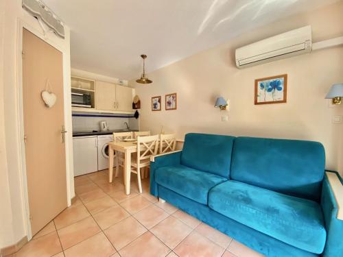 un salon avec un canapé bleu et une cuisine dans l'établissement Joli 2 pièces vue jardin 50m plage Parking Clim, à Menton