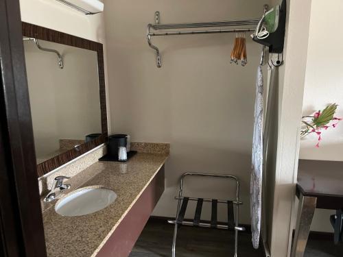 baño con lavabo, espejo y taburete en Royal Inn & Suites, en Mountain Grove