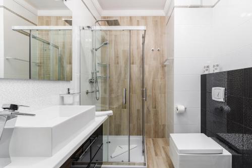 a bathroom with a glass shower and a sink at Apartament Osiedle Bursztynowe Bałtycka by Renters in Kołobrzeg