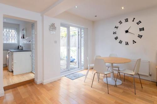 a dining room with a table and a clock on the wall at Fully Equipped 4 Bedroom House with large Garden in Hendon
