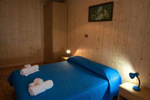 a bedroom with a blue bed with towels on it at Appartamenti Patrizia in San Pietro di Cadore