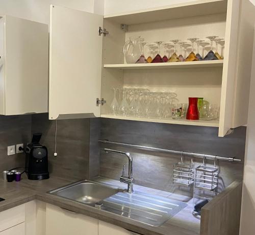 a kitchen with a sink and glasses on shelves at Confort Home - Disneyland Paris à 10 minutes à pied- Marne la Vallée- Paris in Serris