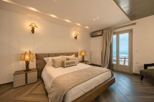 um quarto com uma cama e uma grande janela em SANTORINI GRAND LUXURY VILLAS em Imerovigli