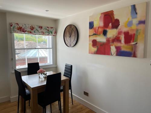 a dining room with a table and a clock on the wall at The Bank in Lewes