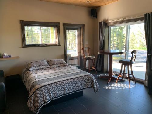 a bedroom with a bed and a table and windows at Les terrasses st aimé in Saint Aime Des Lacs