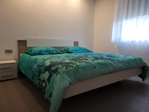 Podbela的住宿－Apartment river Nadiža Podbela，一间卧室配有一张带绿色棉被的床和窗户。