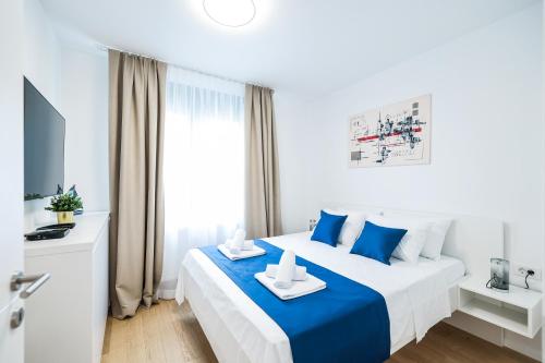 una camera da letto bianca e blu con un letto e una TV di Premium Residence Ventus Rosa - Bora Penthouse a Zara (Zadar)