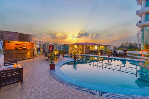 a hotel pool with a sunset in the background at The Solitaire in Dehradun