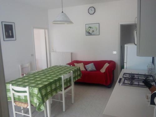 ein Wohnzimmer mit einem Tisch und einem roten Sofa in der Unterkunft Villa Elegante Con Terrazzo E Giardino in San Mauro a Mare