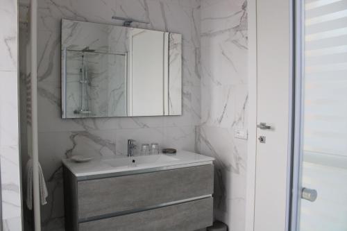 a white bathroom with a sink and a mirror at GF Holiday Suite 3 in Varazze