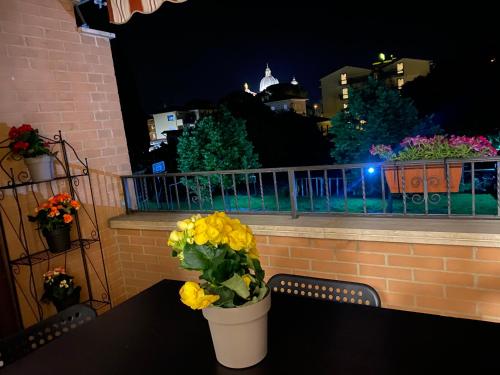 a table with yellow flowers on a balcony at night at Appartamento Antonietta- in Santa Maria degli Angeli