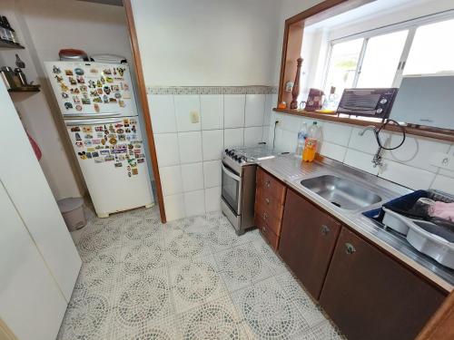 a kitchen with a sink and a refrigerator at Pitangueiras 3 quartos aconchegante , esquina com a praia e shopping in Guarujá