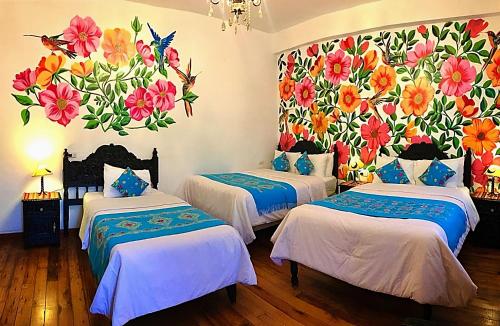two beds in a room with a floral mural on the wall at Casona Dorada Hotel Cusco in Cusco