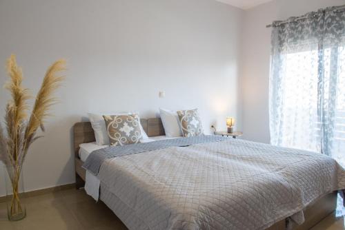 a bedroom with a bed with a blue comforter and a window at Odyssea Seaside Apartment with Sea View and Pool in Kremasti