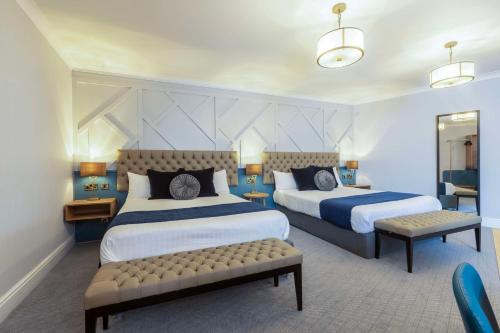 チェスターにあるThe Queen at Chester Hotel, BW Premier Collectionのベッド2台とベンチ付きのホテルルームです。