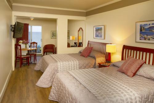 a hotel room with two beds and a dining room at Hotel Motel Belle Plage in Matane