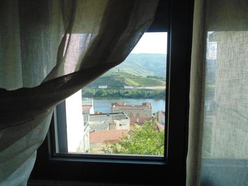 a window with a view of a river and buildings at Casa do Alfaiate - Douro in Peso da Régua