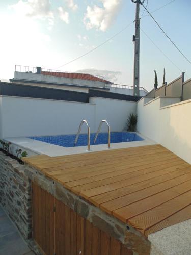 a swimming pool with a wooden deck next to a building at Casa do Alfaiate - Douro in Peso da Régua