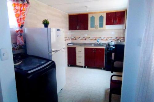 eine Küche mit roten Schränken und einem weißen Kühlschrank in der Unterkunft Apartamento Familiar, cerca al Aeropuerto in Bogotá