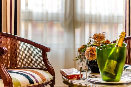 a table with a green vase on a table with a chair at Hotel Regio Cádiz in Cádiz