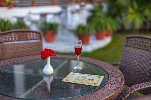 a table with a glass of wine and a flower on it at Pride Premier Solitaire in Dehradun