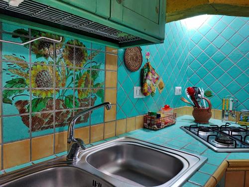 cocina con fregadero y pared de azulejos azules en Il Fenicottero 2 en Masainas