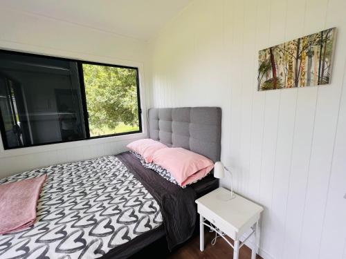 um pequeno quarto com uma cama e uma janela em Three Pines House - Unique Tiny House with Views em Mount Tamborine