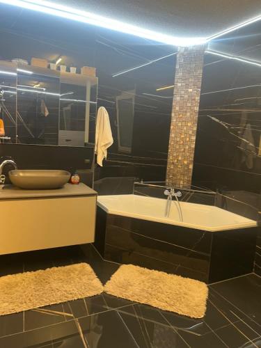 a black bathroom with a sink and a tub at Era Home Deluxe in Murg