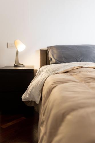 a bedroom with a bed with a lamp on a night stand at [Strategico Rho Fiera-Milano] Vanzago Home Deluxe in Vanzago