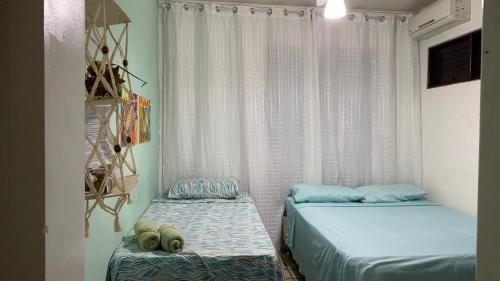 two beds in a small room with a window at Pousada Querência Maceió in Maceió