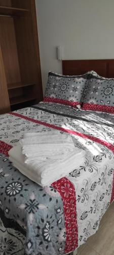 a bed with a red and white quilt on it at Piso As Rodas in Villanueva de Arosa