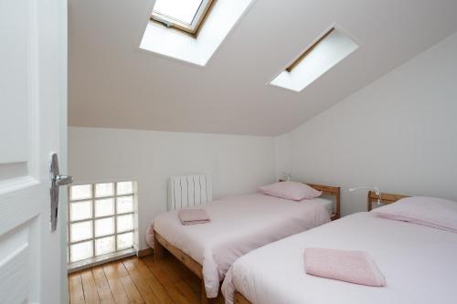 two beds in a room with two windows at Blanc Mesnil centre ville F3 in Le Blanc-Mesnil