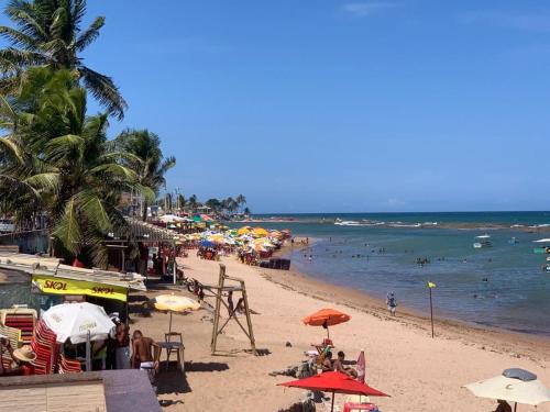plaża z wieloma parasolami i ludźmi w wodzie w obiekcie Casa Completa com piscina, 800m da praia de Jauá w mieście Camaçari