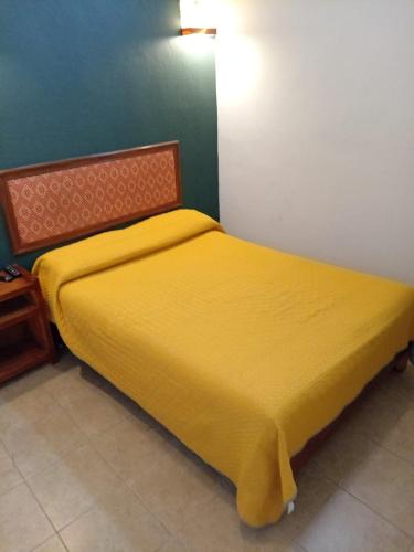 a yellow bed in a bedroom with a green wall at Hospedaje Las Orquideas in Valle de Bravo