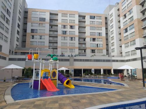 a pool with a playground in front of a building at Park veredas Rio Quente Flavia in Rio Quente