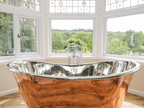 a large tub in a room with windows at Gwern Borter Manor in Conwy
